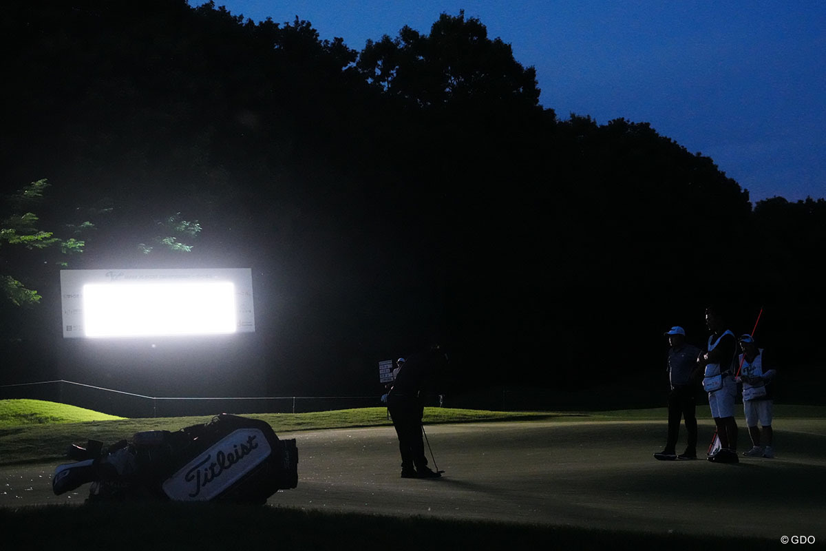 電光掲示板の明かりでパットをする