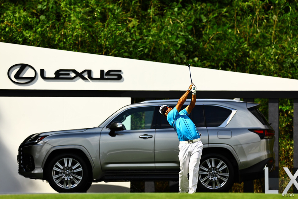 ホールインワン賞のレクサスを背にティショットを打つ松山英樹