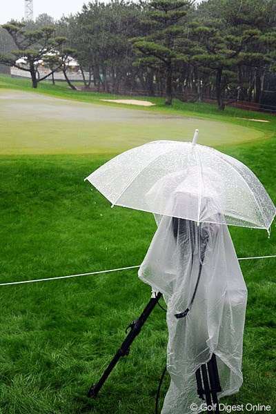 18番グリーンに臨むTVカメラには、ビニールのカッパに加えて傘までが・・・。雨対策万全ということで○。