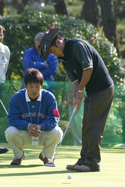 スタート前に江連コーチにパッティングのチェックを受ける片山晋呉。この日は2打後退してしまった。