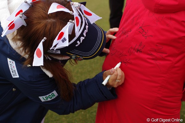 韓国選手からのリクエストに応え、コートにサインをする日本選手。