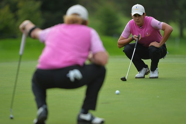 49歳のヒメネス（背中）と協力してラインを読む20歳のマナッセロ。ゴルフの団体戦ならではの光景（Stuart Franklin/Getty Images）